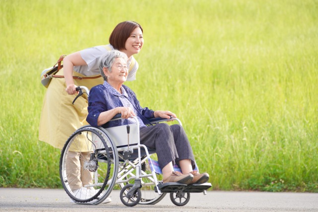 車いすの方を介助者が押して散歩している写真。